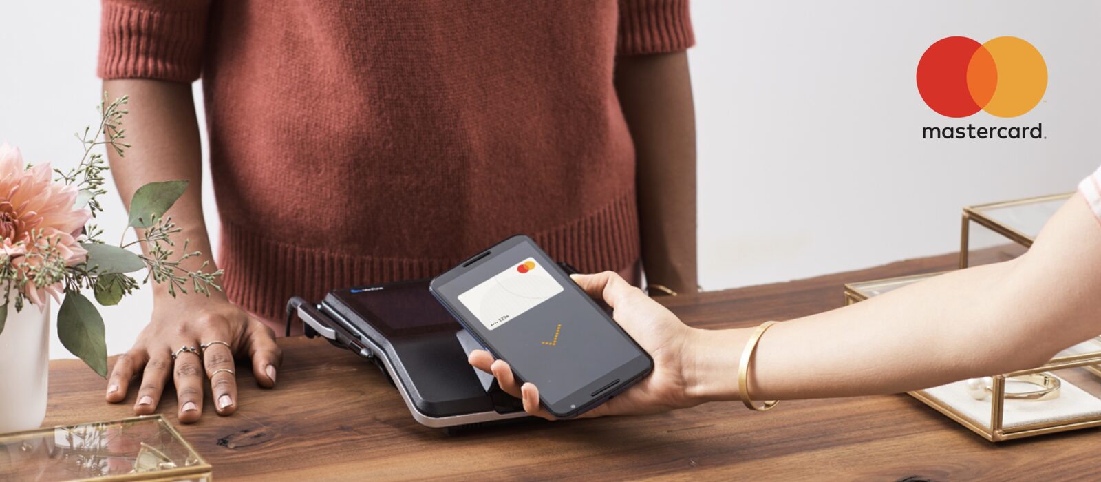 A phone held to a payment terminal at the moment of a contactless Mastercard payment