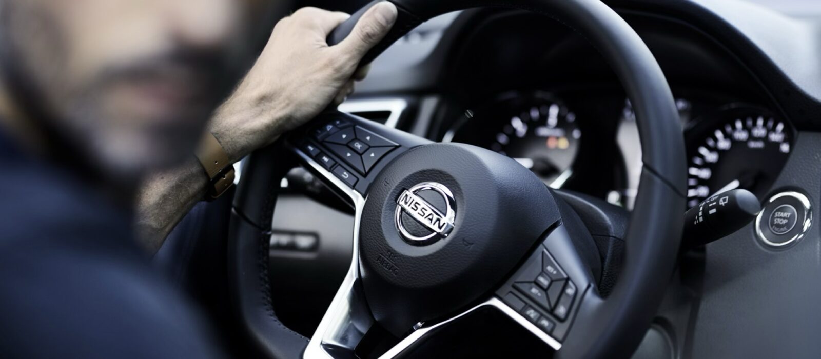 A Nissan dashboard from the driver's seat, the road ahead softly out of focus