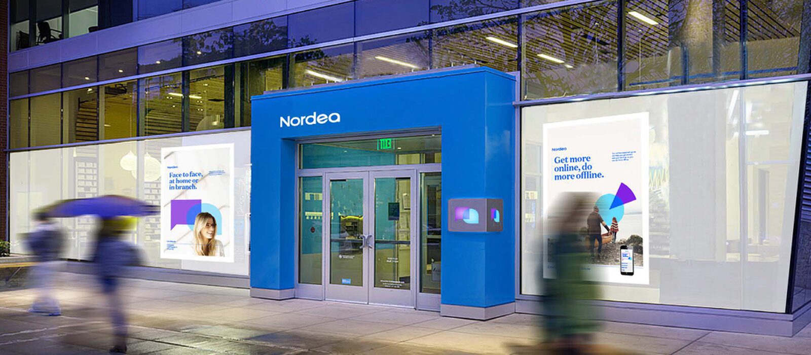 A Nordea branch at dusk, the brand carried across signage and screens as people pass